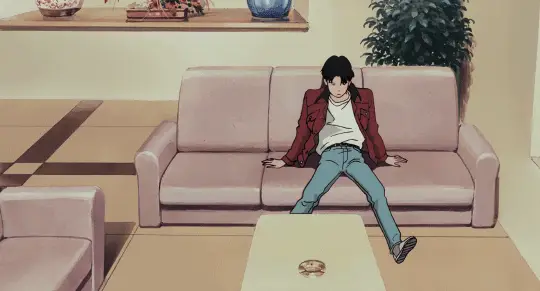 Menikmati Anime di iPhone Gambar seseorang menonton anime di iPhone sambil bersantai di sofa